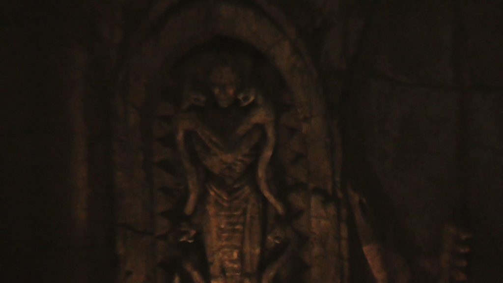 Inside the dark indoor queue, first room has two creepy statues and an arch to enter the next room that looks like a face