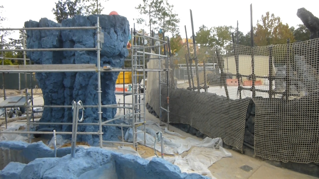 Rock formation on left, portion of outdoor ride path on right behind netting