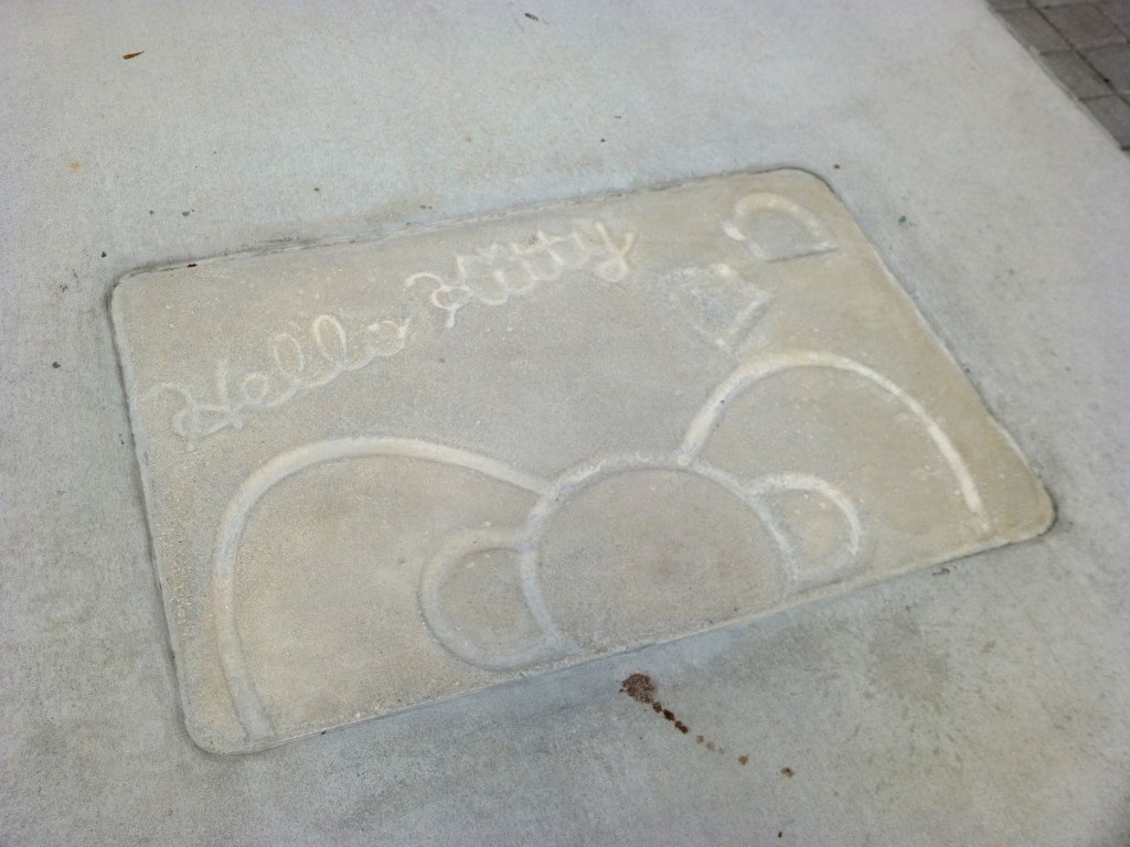 Hello Kitty's signature, footprints, and classic bow in the cement in front of the shop