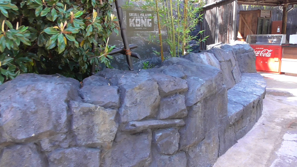 New rock wall facing walkway with built-in bench and hidden speaker playing new area music